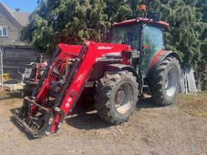 side view of a red tractor with a loader