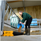 female weranig green wellies and fleece filling up an animal feed trough on the floor of a barn